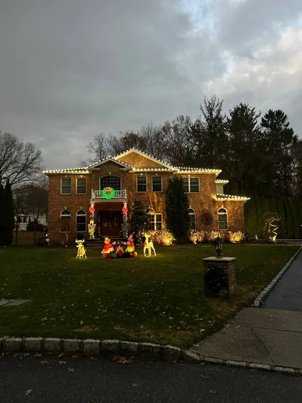 Wreaths, garland and lit walkway on a brick colonial