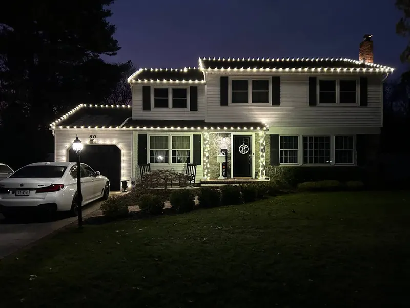 Warm white roofline lighting on a two-story colonial